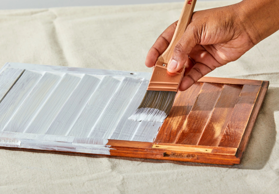 Brushing white paint on a small shutter