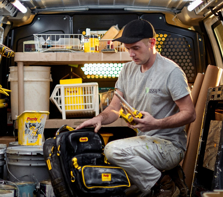 Young professional painter organizing brushes in his work truck.